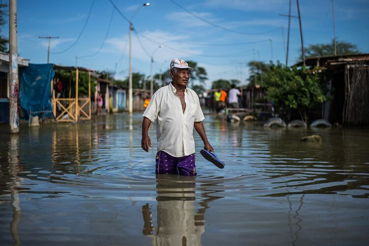 A local resident wades through water on a street in the “El Indio” settlement on the outskirts of Piura, in northern Peru, on March 23, 2017.