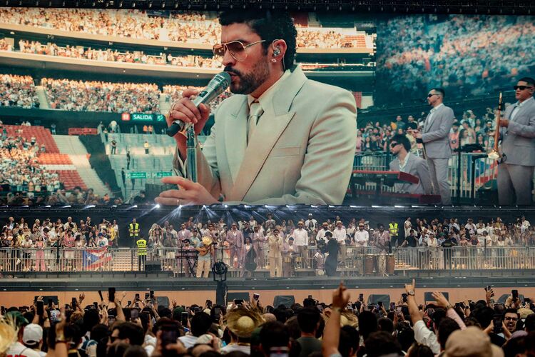 Bad Buny on stage in a packed arena with a jumbotron screen above him