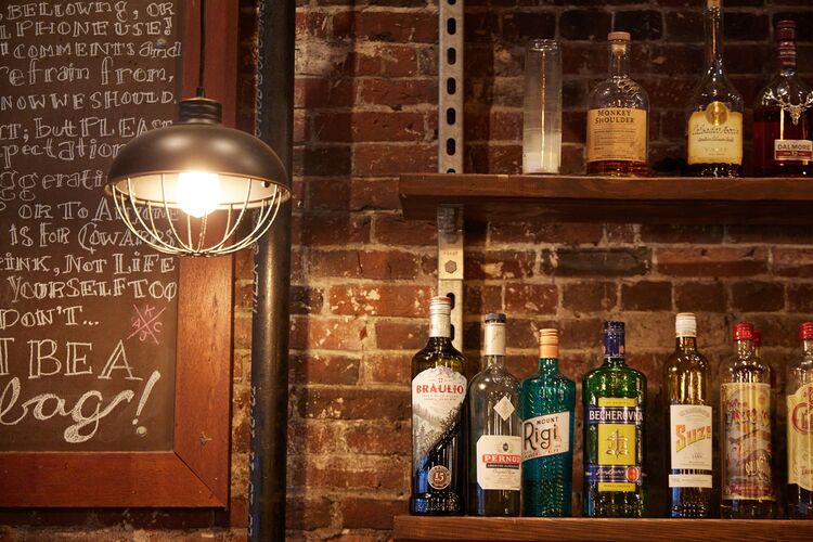Bottles line a shelf against a brick wall at Boston’s jm Curley.