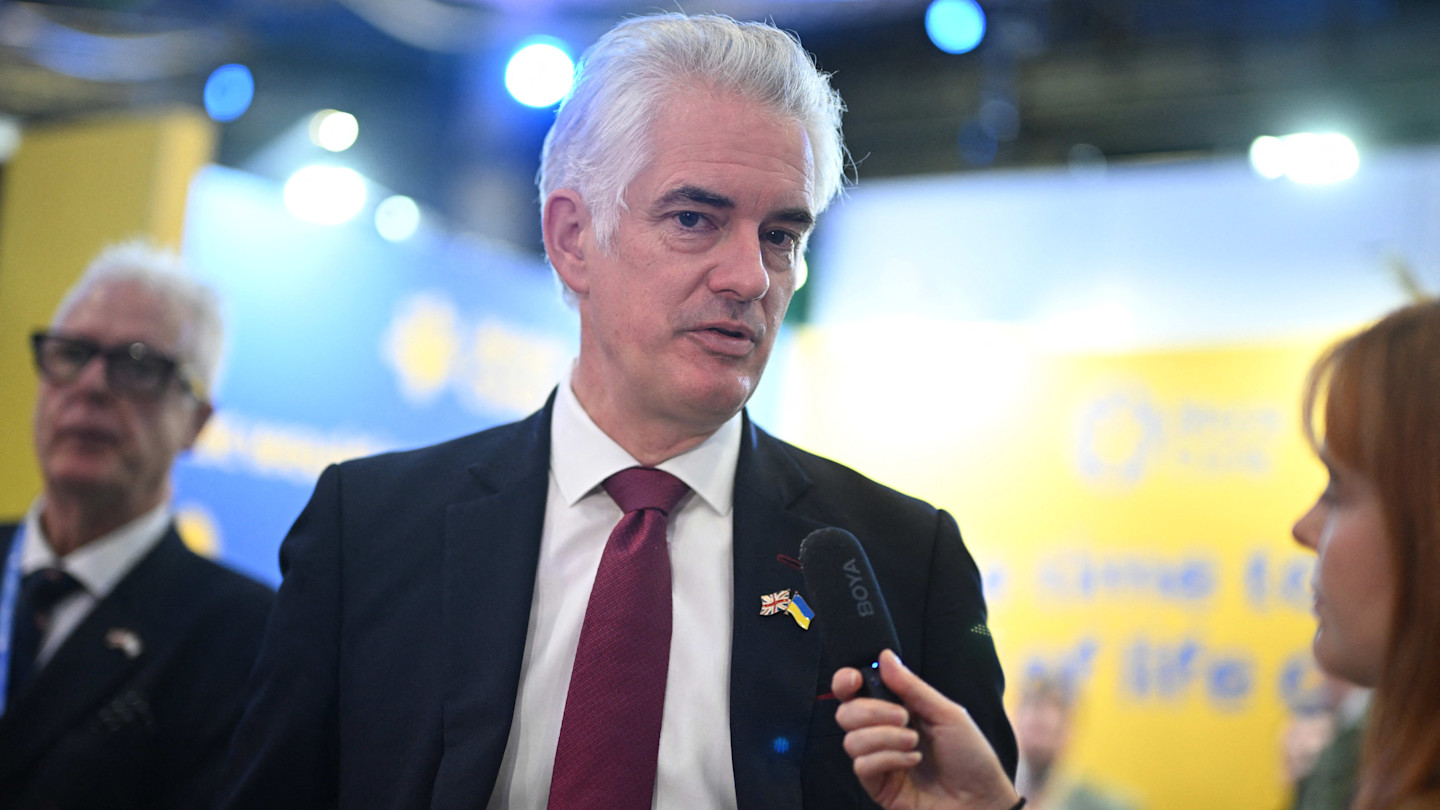 James Cartlidge speaks to a reporter holding a microphone during the Conservative Party conference.