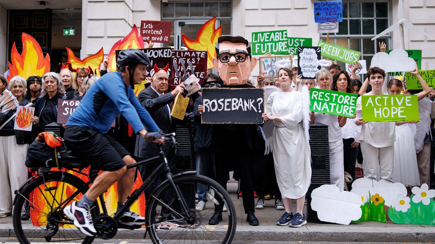 Climate protesters from Fossil Free London stand outside with signs and a large Andy Burnham mascot, some dressed as angels, during a demonstration against the Rosebank oil and gasfield.