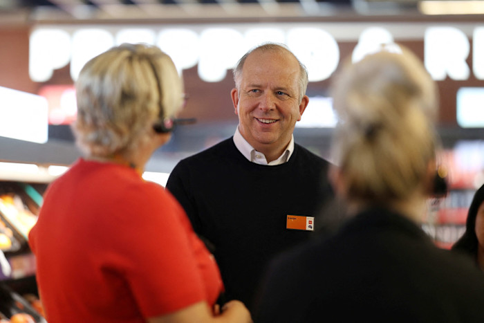 Simon Roberts, Sainsbury's CEO, smiles while talking to employees inside a supermarket.