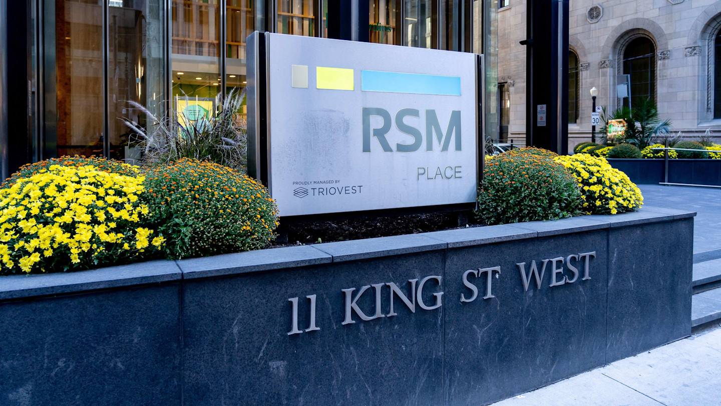 RSM Place sign and address marker at 11 King Street West, surrounded by yellow flowers and shrubs.