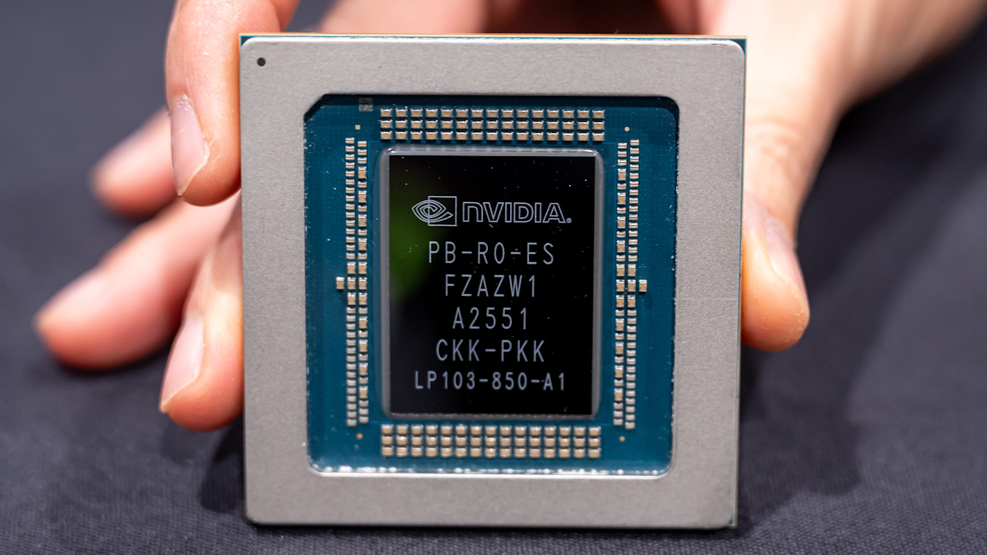 A close-up of a hand holding a Groq 3 LPU chip, showing the Nvidia logo and chip details on its surface.
