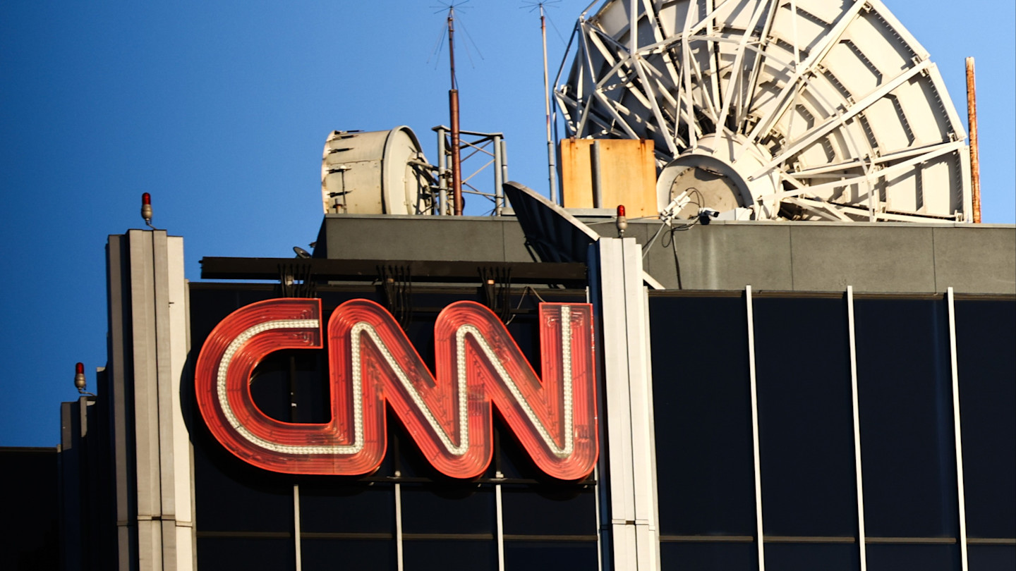 Large red CNN logo on the side of a building, with satellite dishes and antennas visible on the roof.