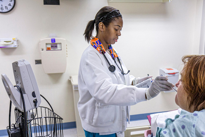 A nurse uses a thermometer to take the temperature of a patient in a private hospital room.
