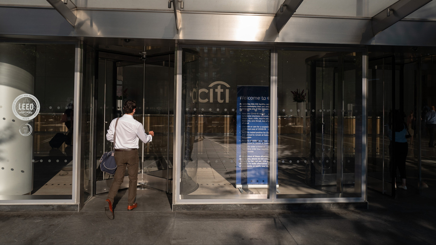 A person carrying a bag enters the glass revolving door at Citigroup headquarters, with the Citi logo visible inside