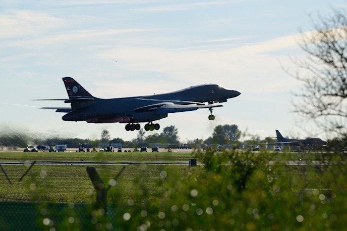 A Rockwell B1 Lancer heavy bomber takes off from a runway at RAF Fairford with landing gear extended.