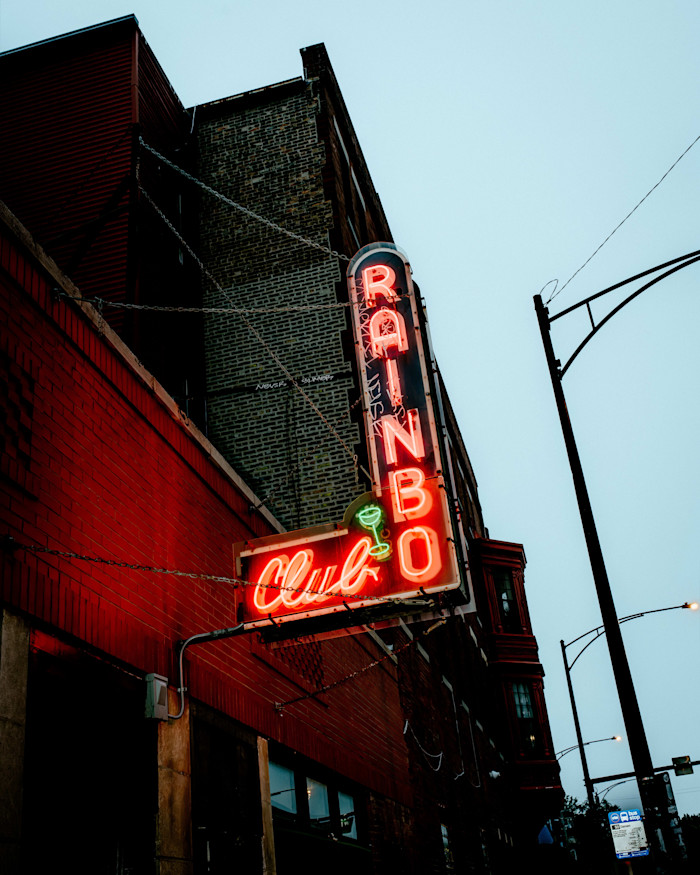 Neon sign reading "Rainbow Club" with a green martini glass, mounted on the brick exterior of a bar in Wicker Park, Chicago.