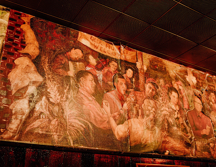 A mural at Simon’s Tavern shows Simon Lundberg in the lower left and painted patrons above the bar.
