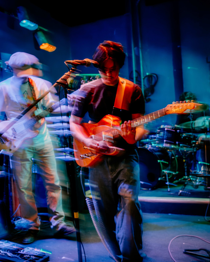 Members of Bike Thief perform on stage with colorful lighting and motion blur during a set at Phyllis Musical Inn.