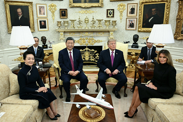Xi Jinping and Peng Liyuan sit with Donald Trump and Melania Trump during a meeting in the Oval Office. A model aeroplane is on the table