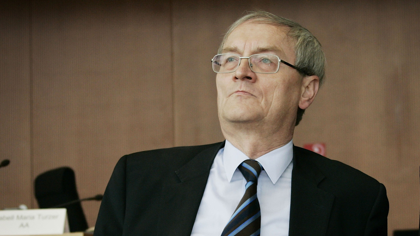 August Hanning wearing a suit and striped tie, seated and looking upward during a Bundestag hearing.