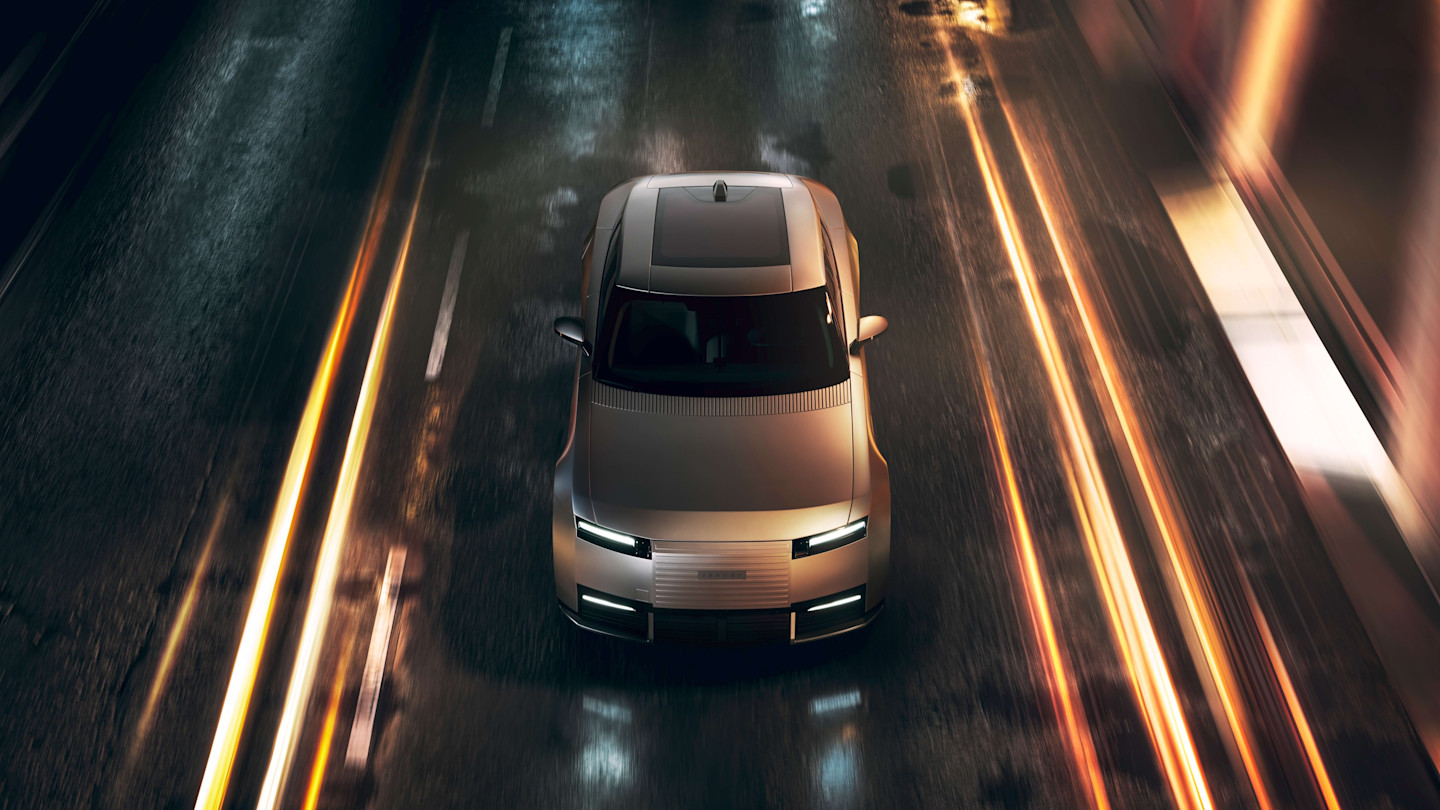 Jaguar Type 01 EV seen from above driving on a wet city street at night