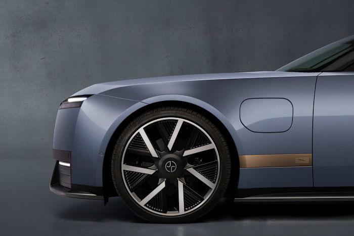 Front side view of a Jaguar Type 01 EV, showing a sleek blue body, large alloy wheel