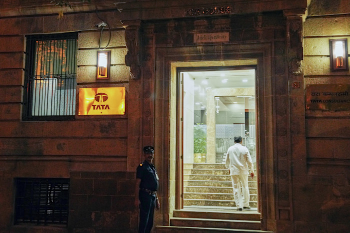 Entrance to Tata Consultancy Services office in Mumbai at night, with a security guard standing outside and a man walking inside