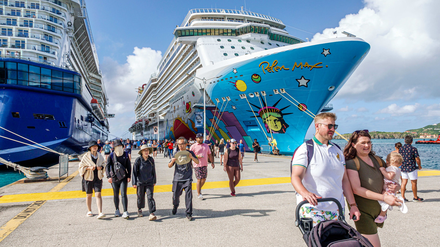 Cruise passengers walk on the pier between the Norwegian Breakaway and Celebrity Eclipse ships docked in Sint Maarten.