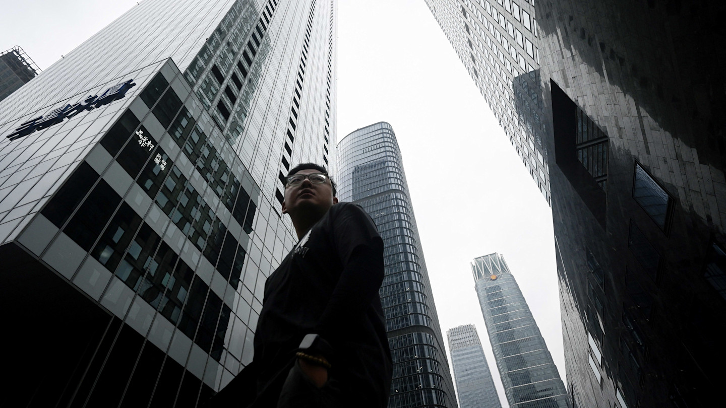 A man walks among tall skyscrapers in Beijing’s Central Business District.
