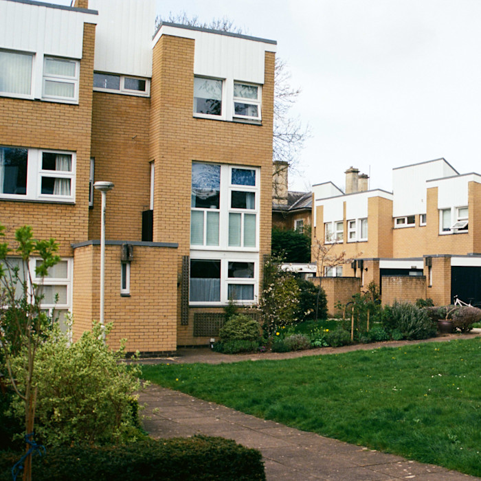 Brick residential buildings with large white-framed windows and well-kept green lawns in front.
