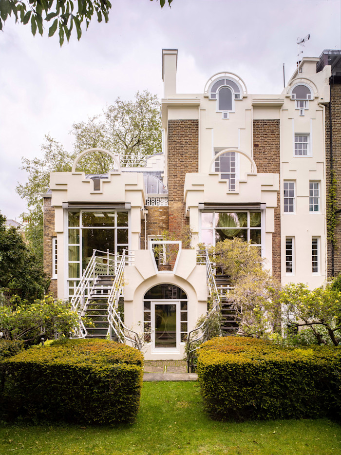 The garden facade of The Cosmic House features large windows and repeated arch motifs symbolising a family of four, with symmetrical stairs leading to the garden.
