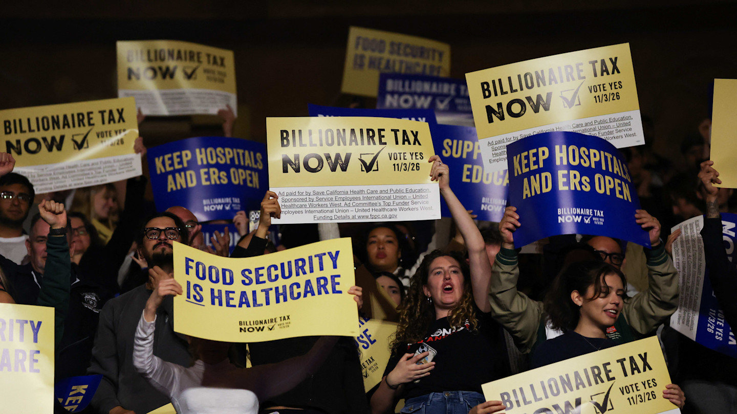 Cheering attendees hold signs reading “Billionaire Tax Now,” “Keep Hospitals and ERs Open," and “Food Security is Healthcare.”