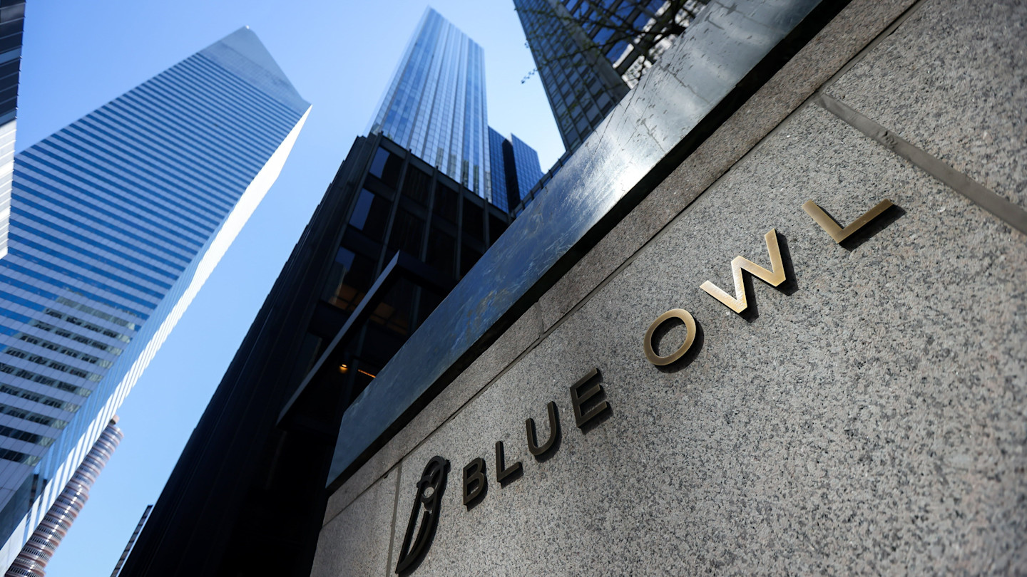 Blue Owl signage displayed on a stone wall outside the Seagram Building, with tall skyscrapers in the background.