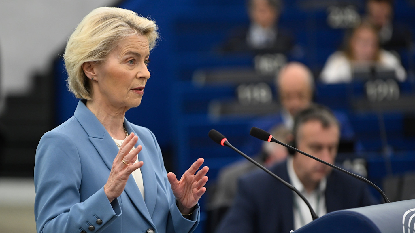 Ursula von der Leyen speaks at a podium with two microphones during a debate, gesturing with her hands.