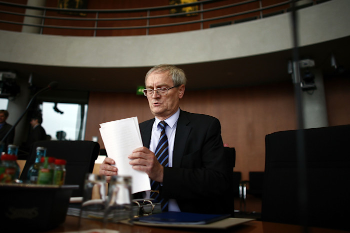 August Hanning sits at a desk holding documents during a Bundestag hearing.