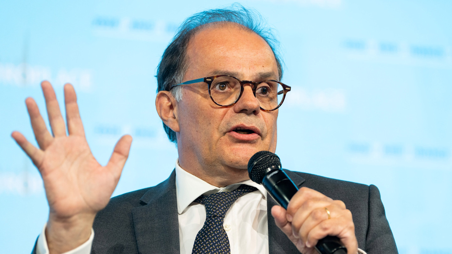Emmanuel Moulin speaks into a microphone and gestures with his hand during the Paris Finance Forum.