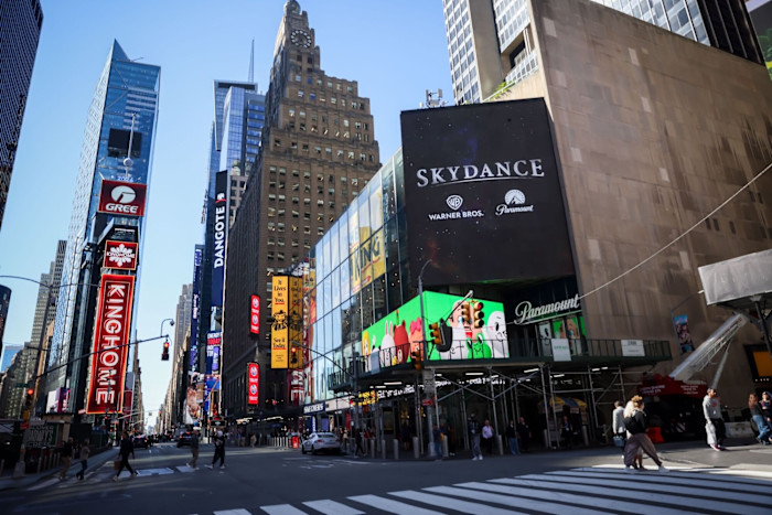 Large Skydance billboard in Times Square displays Warner Bros and Paramount logos above a busy street with pedestrians crossing.