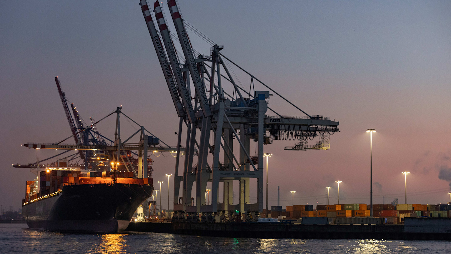 A docked container ship as cranes unload cargo at dusk in the Port of Hamburg.