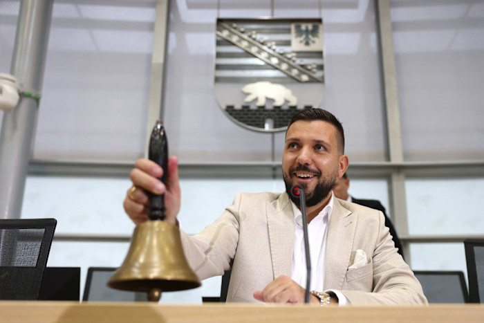 Tobias Rausch smiles as he rings a bell at the podium during a parliamentary session in Saxony-Anhalt.