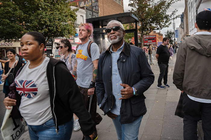 People walking along a busy street in Holborn and St Pancras, with various shops and a bus stop in the background.