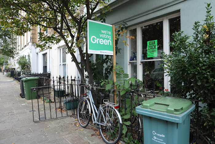 A Green Party campaign placard and a "Vote Zack Polanski" sign are displayed outside a house in Kentish Town, London.
