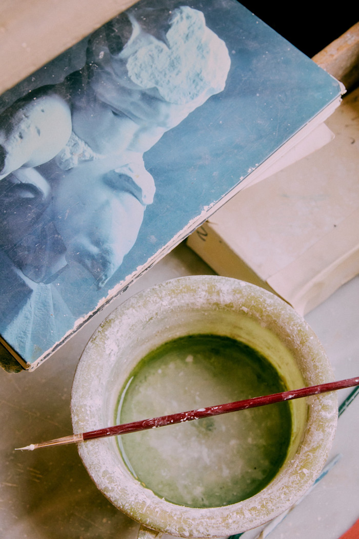 A retouching brush beside the atelier’s catalogue