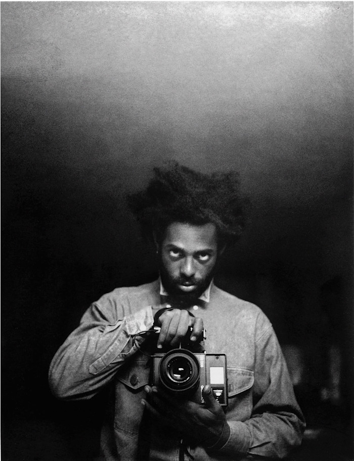 Arthur Jafa holds a camera and looks directly into the lens in this black-and-white self-portrait.