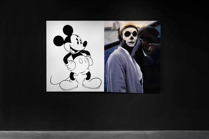 A large artwork by Arthur Jafa pairs a black-and-white Mickey Mouse illustration with a photograph of a person wearing skull face paint and a headband, standing beside another figure.