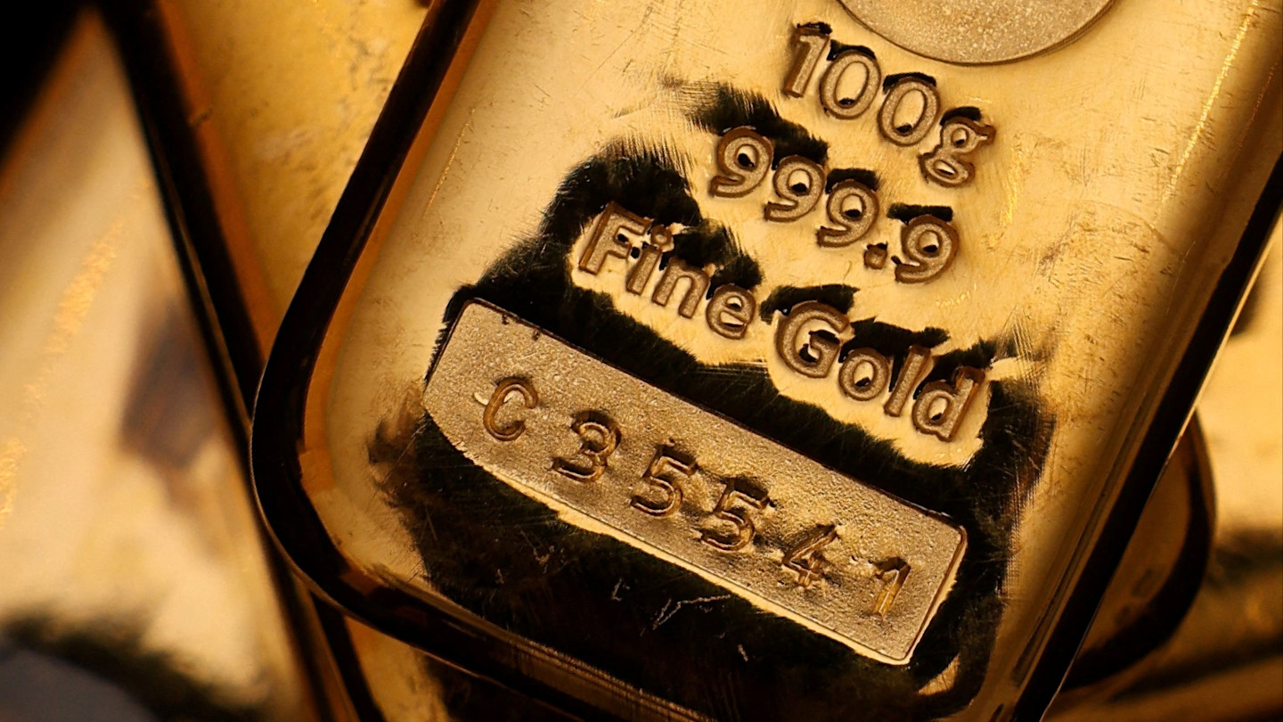 Close-up of stacked gold bullion bars showing engraved markings, including weight, purity, and serial number.