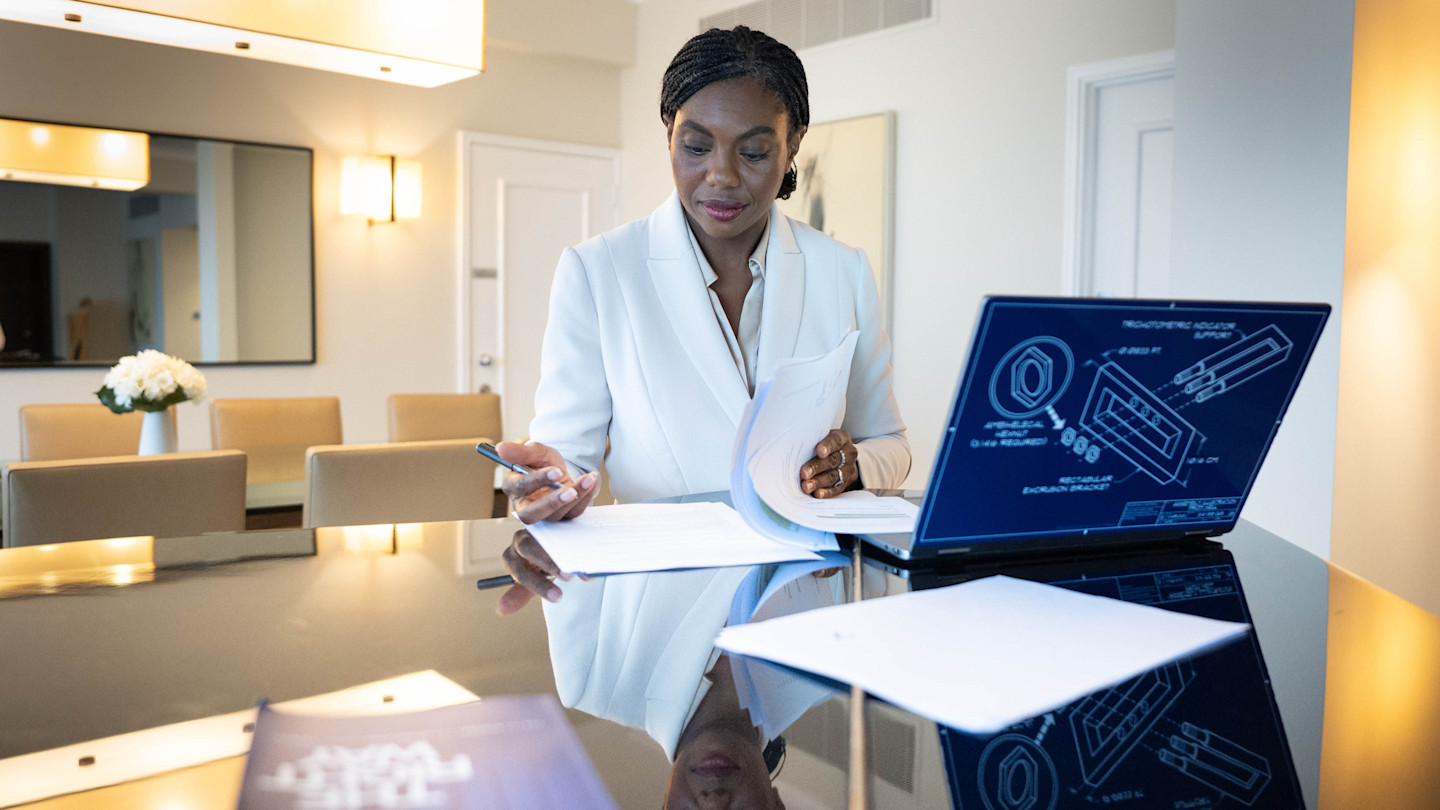 Kemi Badenoch reviews documents and makes notes at a desk in a hotel room, with a laptop and papers in front of her.