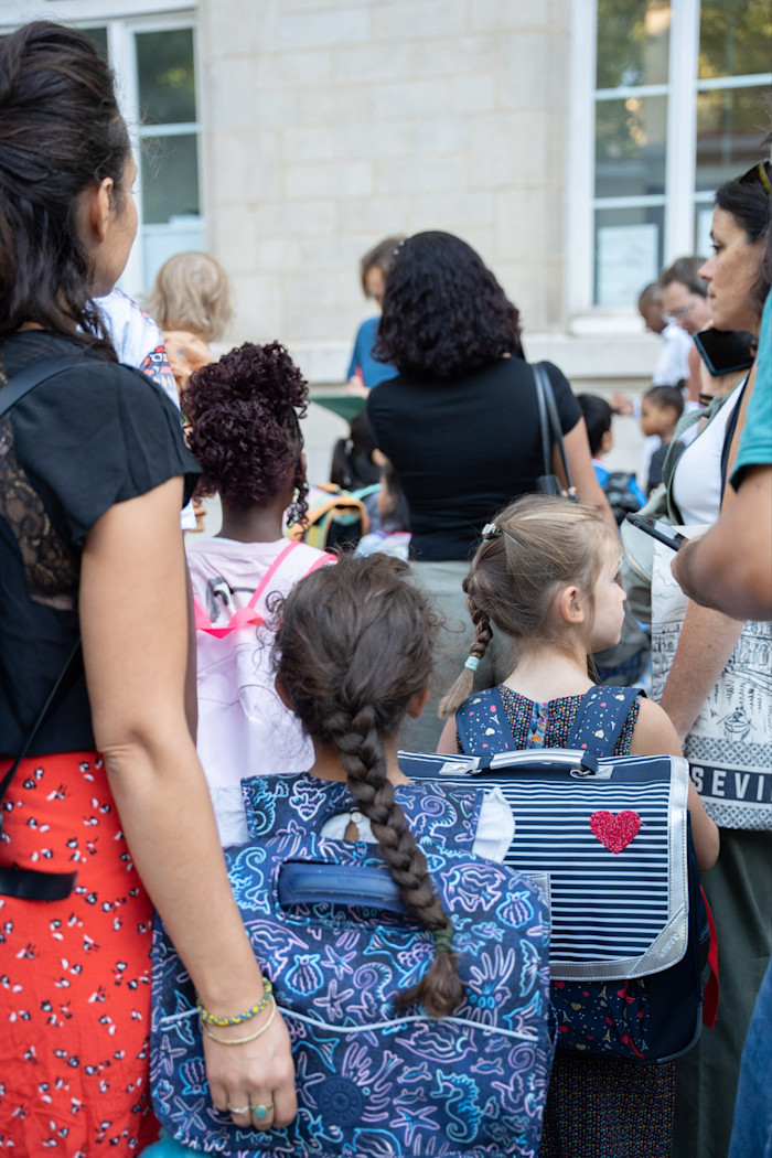 Mothers and small children with little backpacks stand in the playground