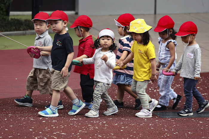 Kindergarten group wearing red caps walking on a playground