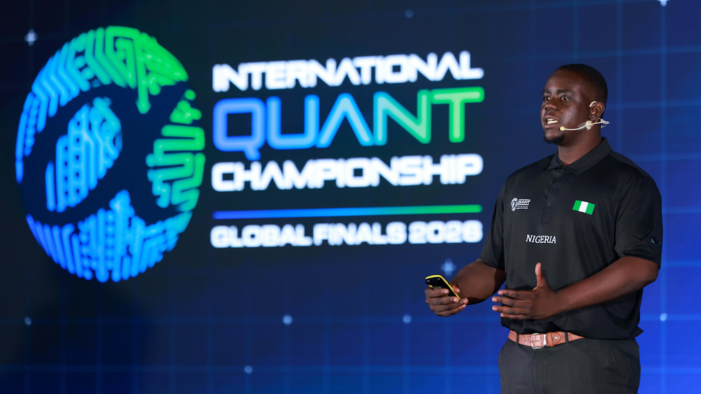 Victor Ayebameru speaks on stage at the International Quant Championship 2026, wearing a Nigeria team shirt.