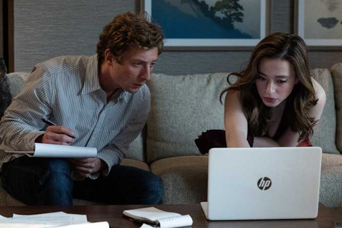Jeremy Allen White as Jeff Horwitz and Mikey Madison as Frances Haugen sit on a couch, focused on a laptop and taking notes.