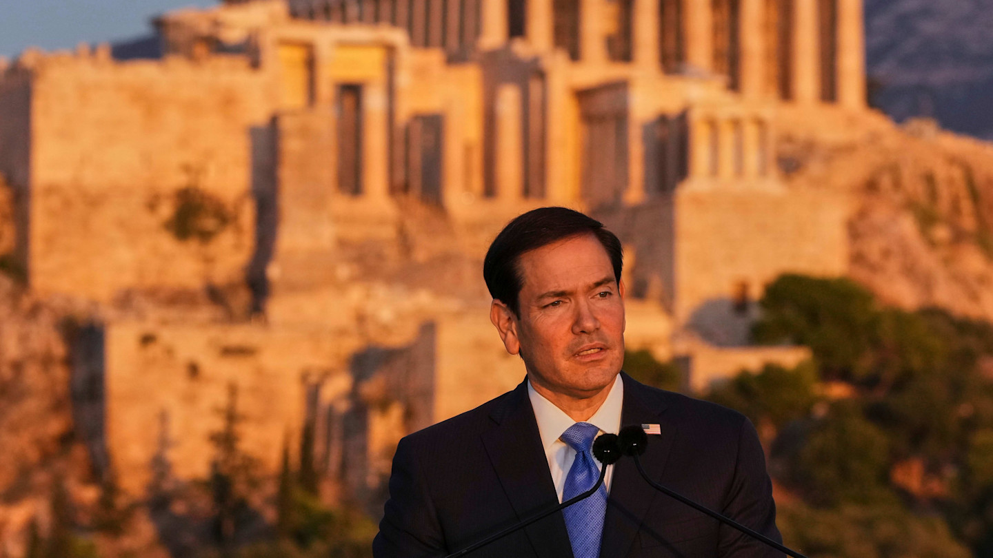 Marco Rubio speaks at a podium outdoors with the ancient Parthenon temple on the Acropolis visible in the background.