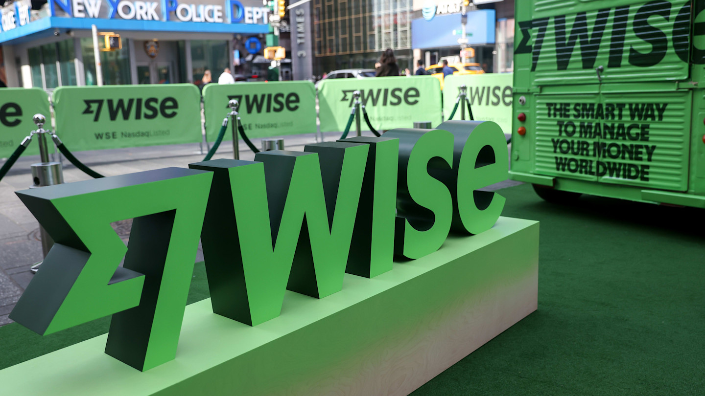 Large green 3D “Wise” logo display and branded barriers in Times Square, with the New York Police Department building in the background.