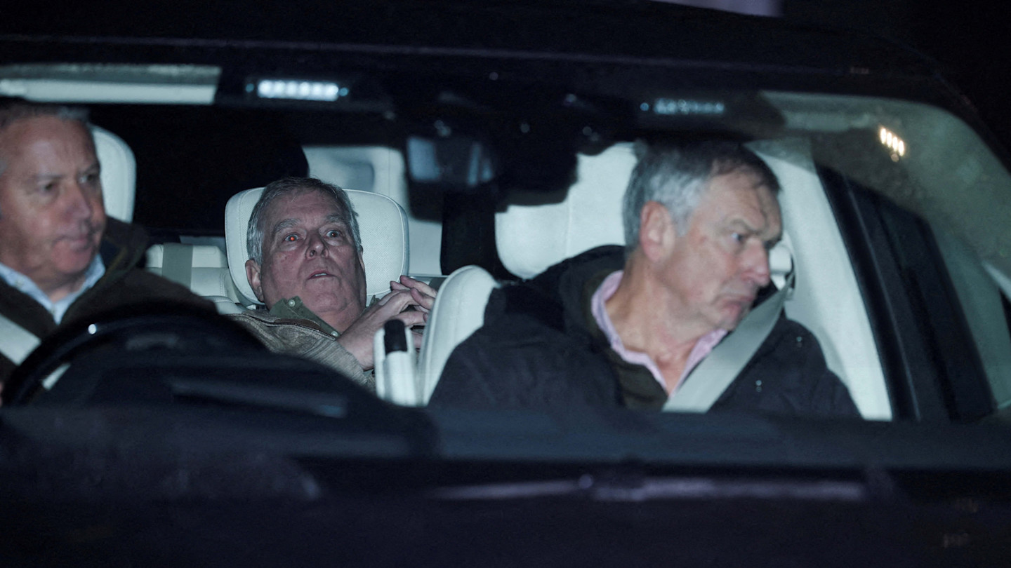Andrew Mountbatten-Windsor sits in the back seat of a vehicle, flanked by two unidentified men.