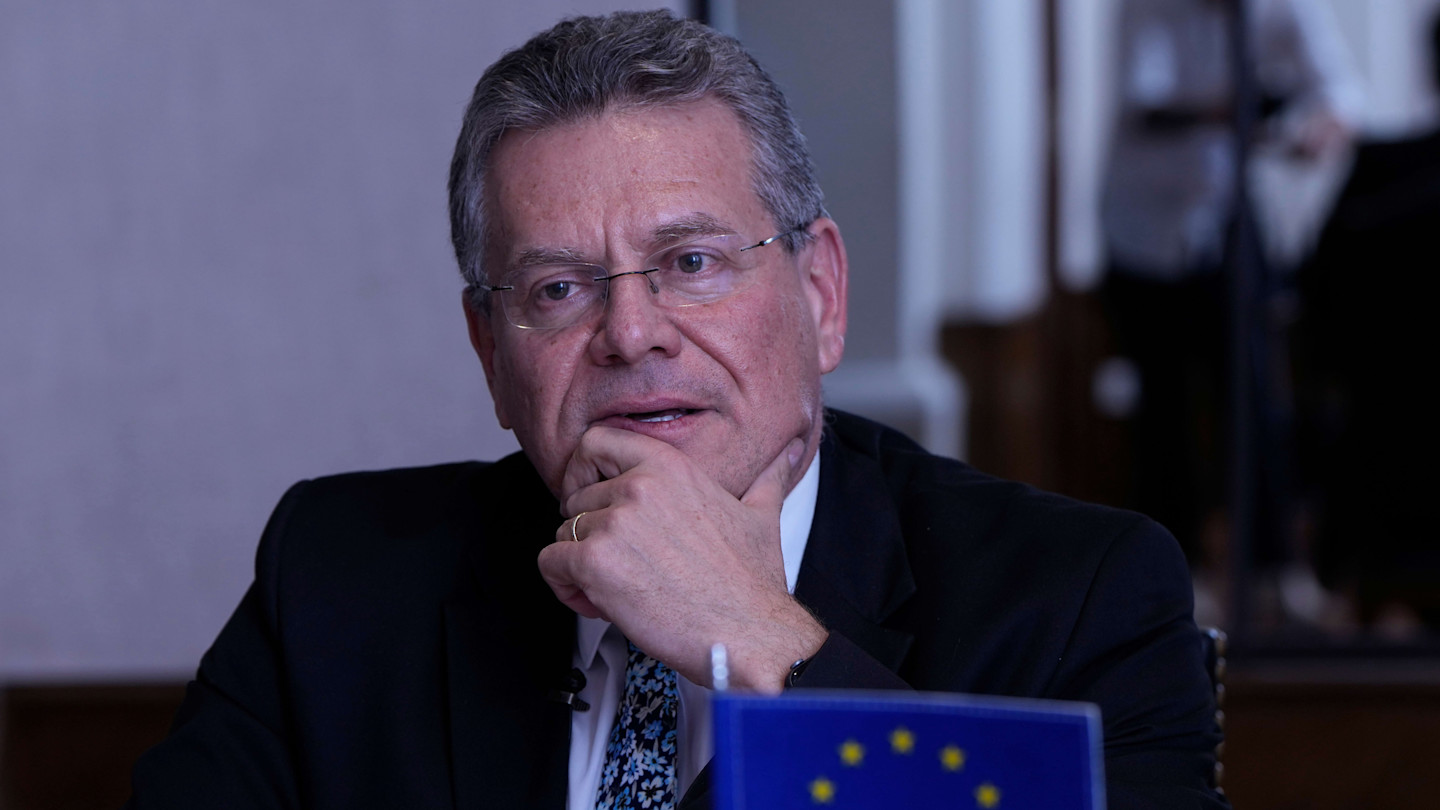 Maroš Šefčovič rests his chin on his hand during an interview, with a European Union flag in the foreground.