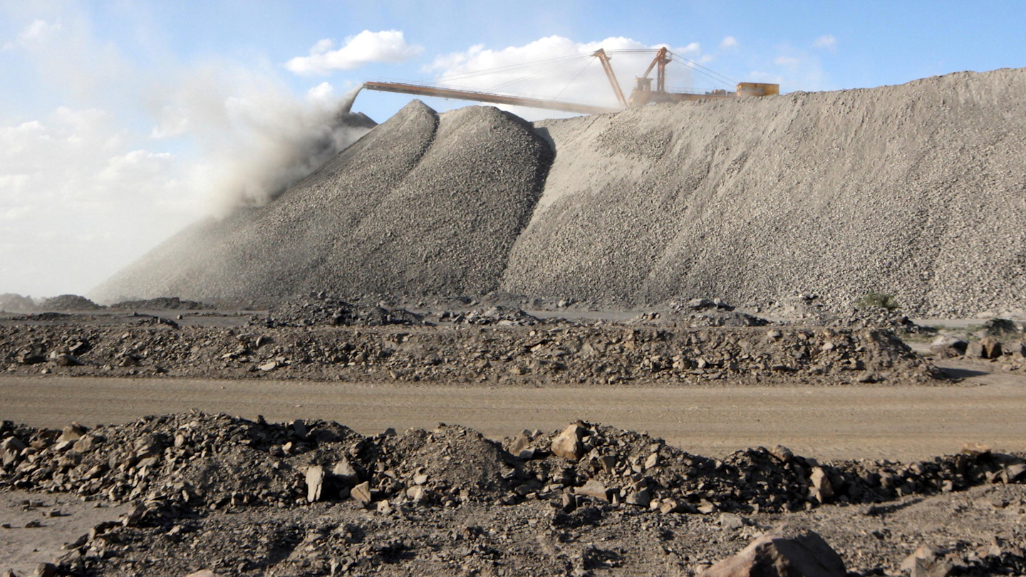 A mining machine releases dust as it deposits rocks onto large piles at the Bayan Obo rare earth minerals mine in Inner Mongolia, China.
