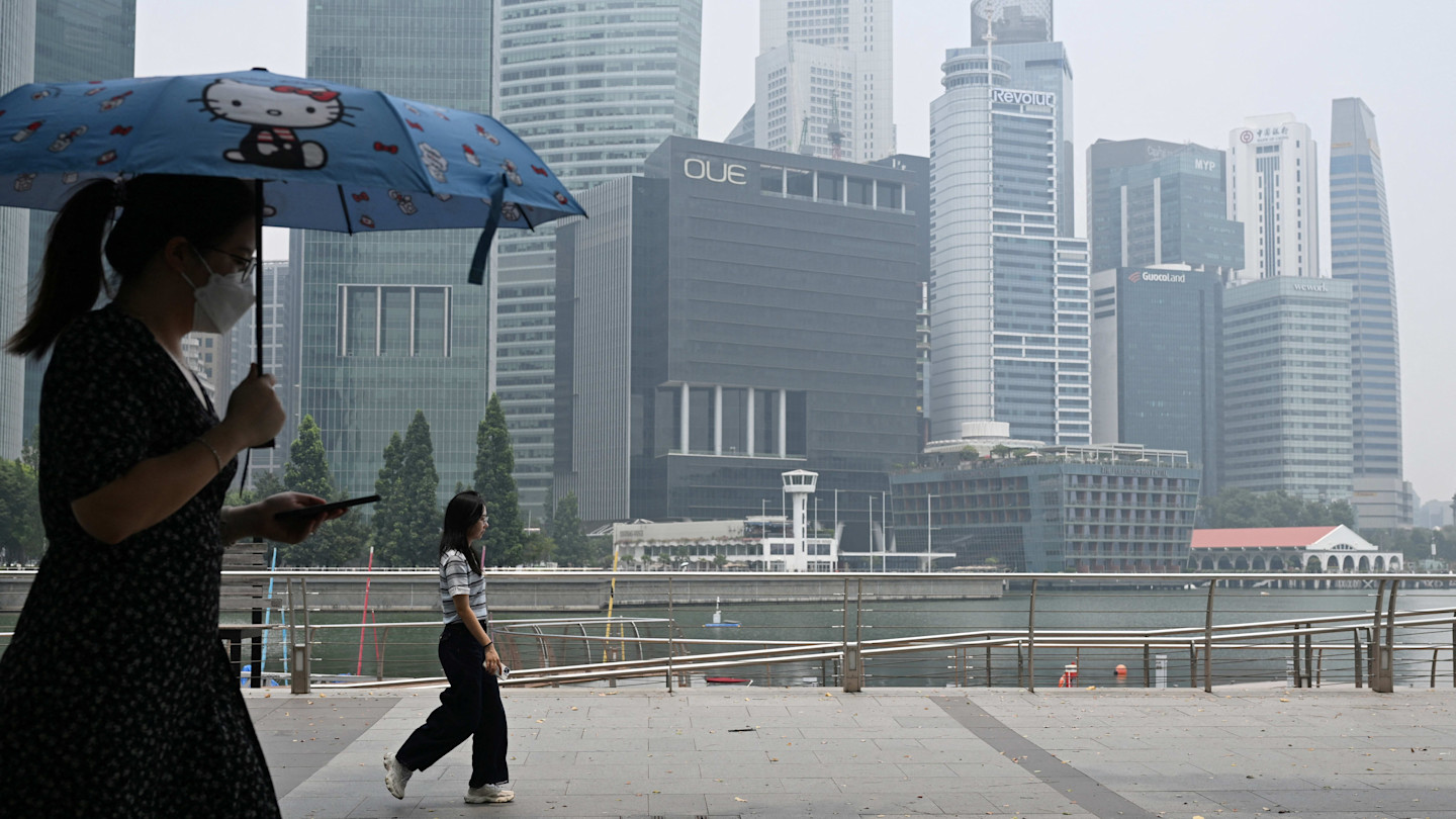 People walk along the boulevard of Marina Bay in Singapore as buildings are shrouded with haze 