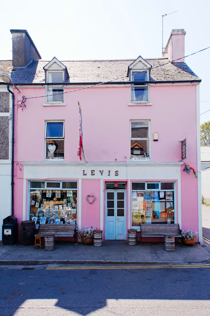 A pink three-storey building with "Levis" above the door, two benches, and colourful posters in the windows.